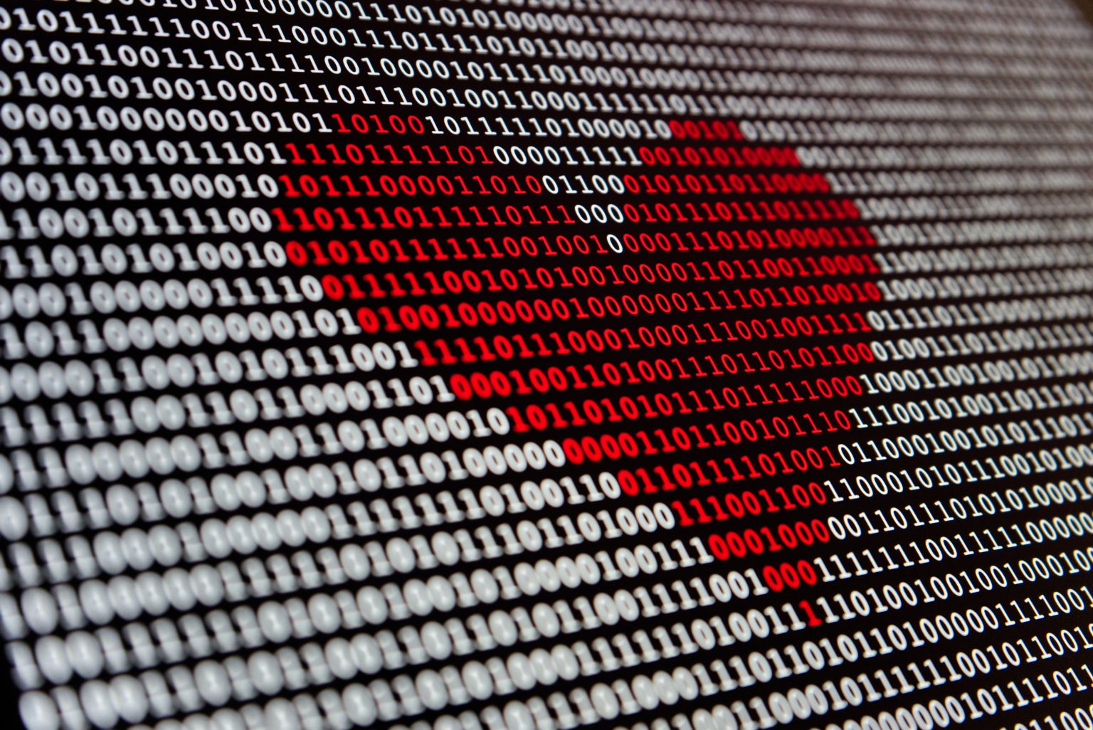 Image depicting red heart drawing in the center of binary code. 
